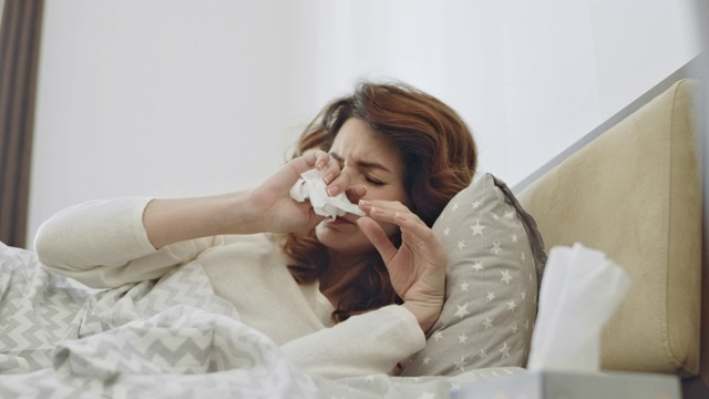 生病的女人在床上感染了咽喉病毒。特写女性的手拿餐巾视频素材