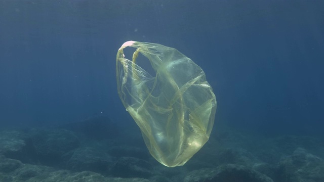 塑料污染，黄色塑料袋在bubuwater。丢弃的塑胶袋在阳光下慢慢漂浮在蓝色的水面下。欧洲地中海漂浮着黄色塑料袋。视频素材