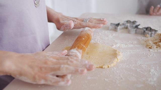 特写的女性的手滚动面团在厨房桌子上烹饪与孩子视频素材