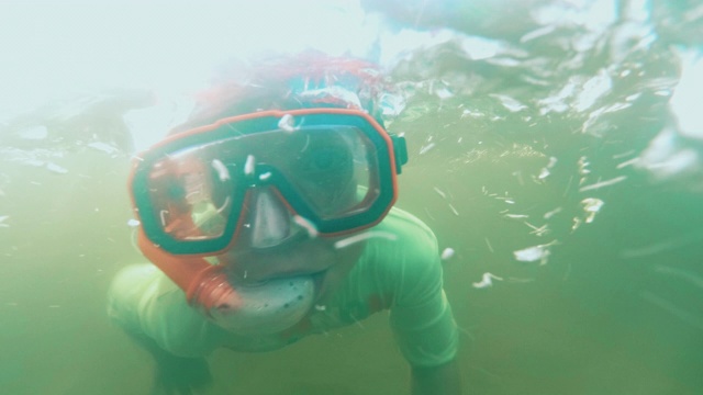 一个9岁的小男孩夏天在湖里跳水。视频素材