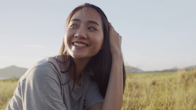 美丽的亚洲女孩是微笑和幸福的，日落在大自然中在夏天的时间视频素材