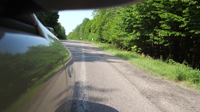 向一辆正在行驶的汽车开枪。汽车沿着森林的道路行驶。4 k缓慢莫视频素材