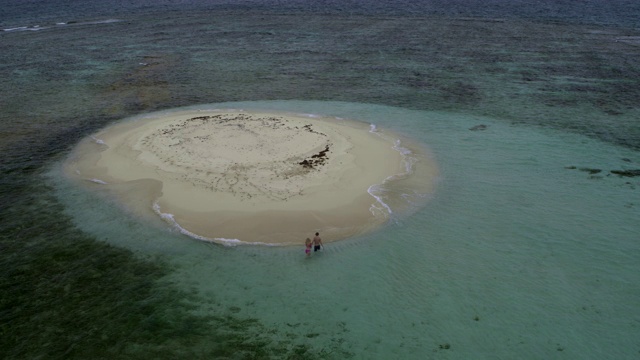 鸟瞰图远距离夫妇散步然后坐在遥远的沙坝海滩/格林纳达视频素材