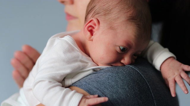 妈妈抱着新生婴儿，轻拍婴儿背部以帮助咳嗽视频素材