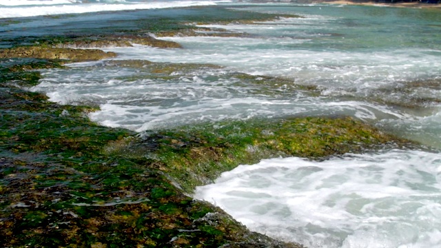 透明的海浪从棕色的岩石上缓缓流下视频素材