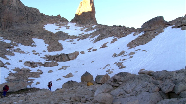 徒步旅行者沿着岩石山脊攀登。视频素材