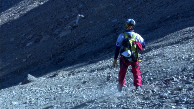 徒步旅行者缓步走下岩石嶙峋的山坡。视频素材