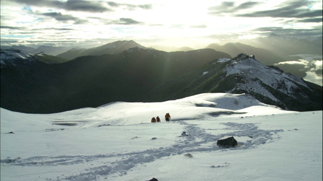 登山者艰难地爬上积雪的山坡。视频素材