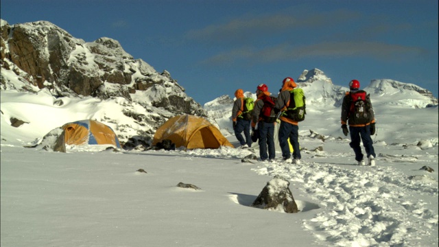 登山者穿过积雪走向大本营的帐篷。视频素材