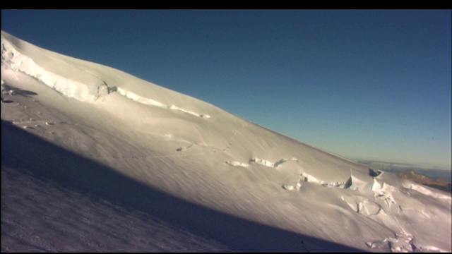 徒步旅行者穿过白雪覆盖的山坡。视频素材