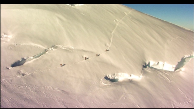 徒步旅行者穿过白雪覆盖的山坡。视频素材