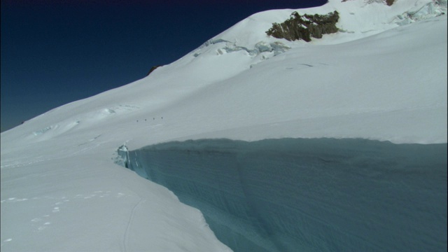 一队徒步旅行者艰难地穿过白雪覆盖的斜坡。视频素材