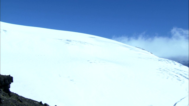 一队登山者艰难地穿过一片广阔的雪原。视频素材