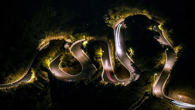 空中的时间推移，山坡上的道路在傍晚穿过森林。九份视频素材