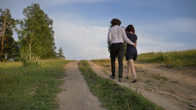 两个年轻人，一个男孩和一个女孩拥抱着爬山，沿着公园的小路视频素材