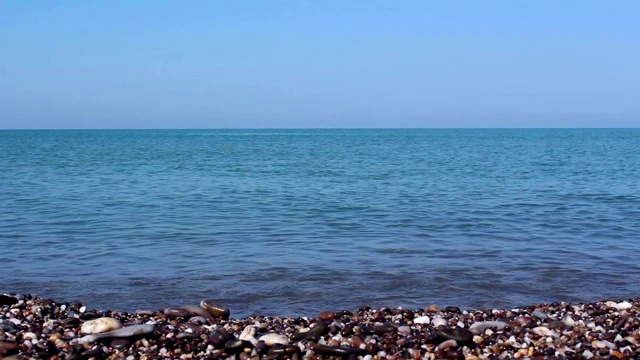 可以看到大海和布满岩石的海岸，还有海卵石。大海和清澈的蓝色水。岩石海岸上的海浪。视频素材