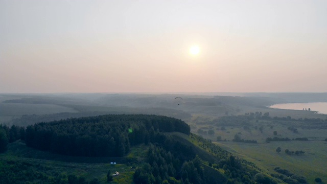 一个人驾着滑翔机在田野上空翱翔。滑翔伞在天空。视频素材