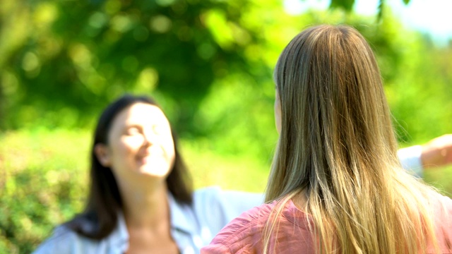 黑发女孩高兴地看到她的金发朋友，女孩拥抱户外，特写视频素材