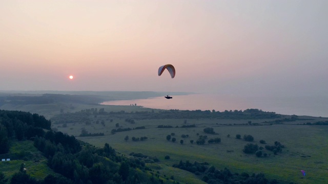 在夕阳背景下，运动员在空中的滑翔伞上飞行。滑翔伞，动作，极限运动概念。视频素材