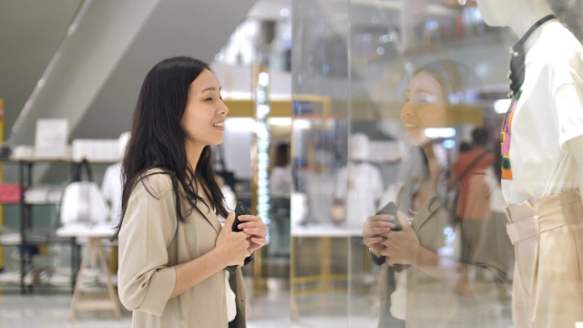 购物成瘾的亚洲女人站在商店橱窗前视频素材