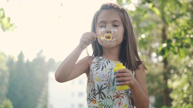 孩子在公园里吹肥皂泡。一个快乐的小女孩在户外的肖像视频素材