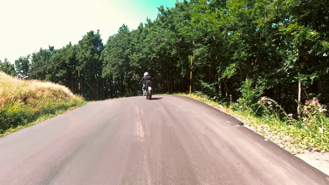 骑摩托车的人在山区的乡村公路上视频素材