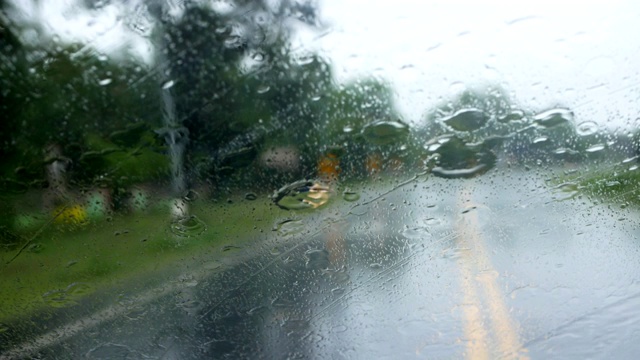 下雨的时候，开车在路上，雨点滴落在玻璃窗上视频素材