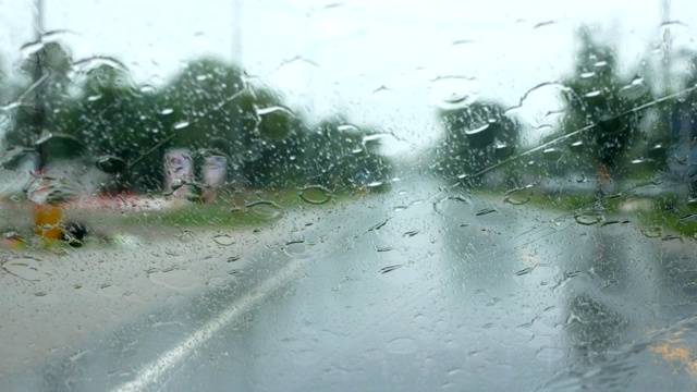 下雨的时候，开车在路上，雨点滴落在玻璃窗上视频素材