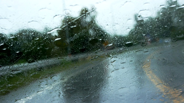 下雨的时候，开车在路上，雨点滴落在玻璃窗上视频素材