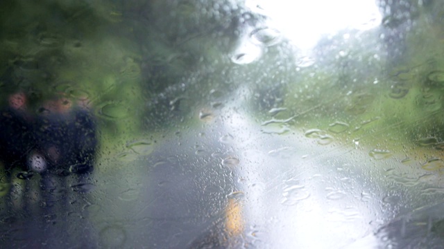 下雨的时候，开车在路上，雨点滴落在玻璃窗上视频素材