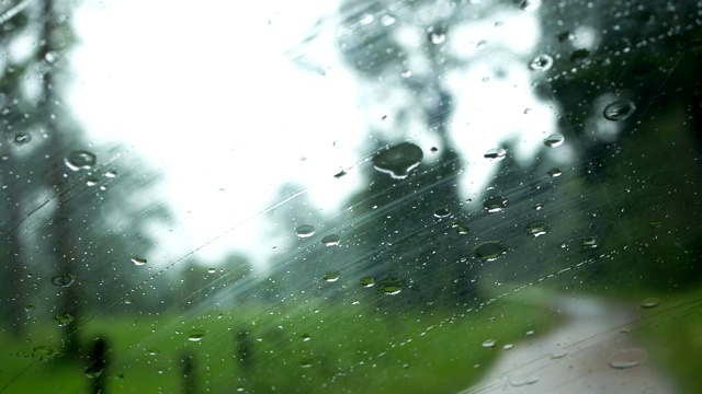 下雨的时候，开车在路上，雨点滴落在玻璃窗上视频素材