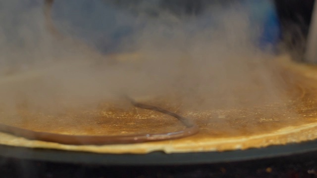 慢镜头小贩在巴黎街头的金属煎锅上做薄饼视频素材