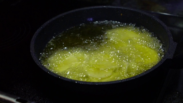 慢动作炸薯条烹饪。土豆放入滚烫的油中。快餐视频素材