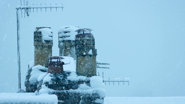 被雪覆盖的屋顶上的烟囱和天线视频素材