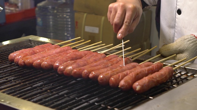 缓慢的运动。人们在亚洲夜市烹饪烧烤香肠视频素材