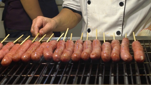 缓慢的运动。人们在亚洲夜市烹饪烧烤香肠视频素材