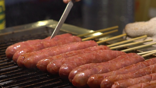 缓慢的运动。人们在亚洲夜市烹饪烧烤香肠视频素材