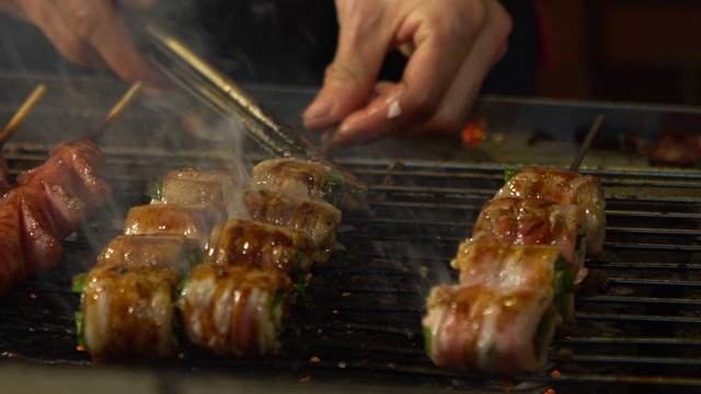 慢镜头卖主烹饪培根、葱包钢烤架，夜市视频素材