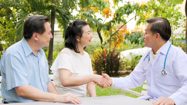 医生和成熟夫妇病人在花园里握手。视频素材