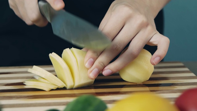 在砧板上切土豆。关闭了。环的土豆。切些蔬菜做沙拉。健康食品。视频素材