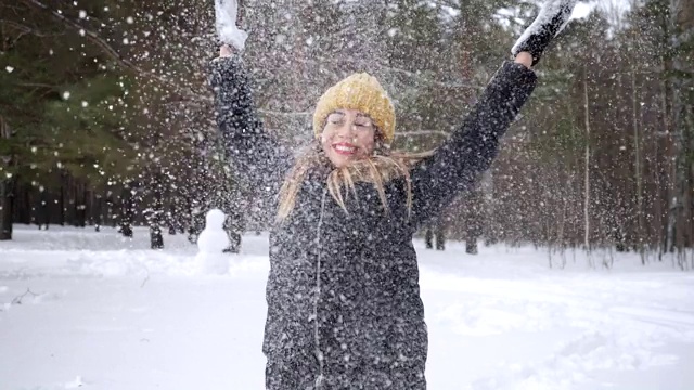 一个女人正在向空中抛雪，用慢镜头享受寒冷的季节。视频素材