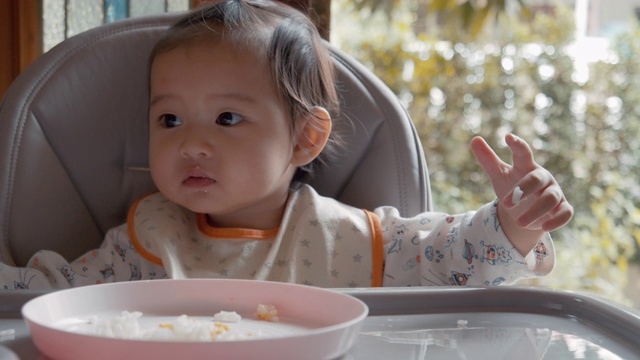 小女孩在家里的客厅里吃着妈妈喂给她的食物。视频素材