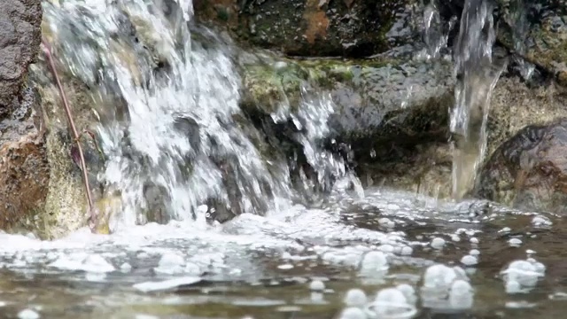 小溪在长满苔藓的岩石上缓缓流淌。山河森林视频素材