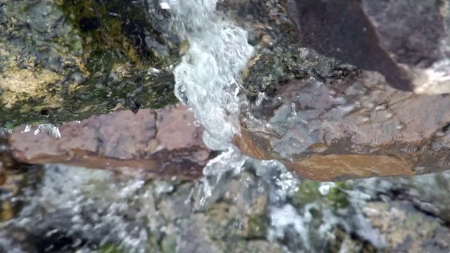 小溪在长满苔藓的岩石上缓缓流淌。山河森林视频素材