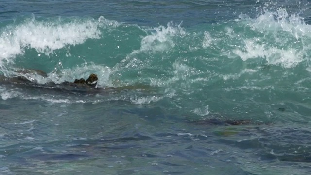 汹涌的泡沫状海浪破碎的慢动作。海浪打在岩石上视频素材