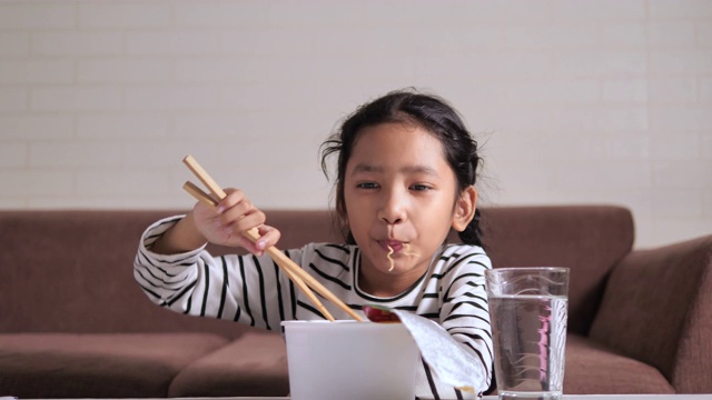 亚洲小女孩用筷子吃辣可口的方便面与幸福选择焦点浅景深视频素材