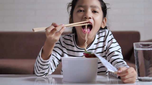 亚洲小女孩用筷子吃辣可口的方便面与幸福选择焦点浅景深视频素材