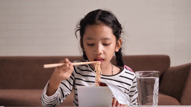 亚洲小女孩用筷子吃辣可口的方便面与幸福选择焦点浅景深视频素材