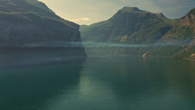 空中飞过盖兰格峡湾平静的水面上的薄雾，背景是群山视频素材