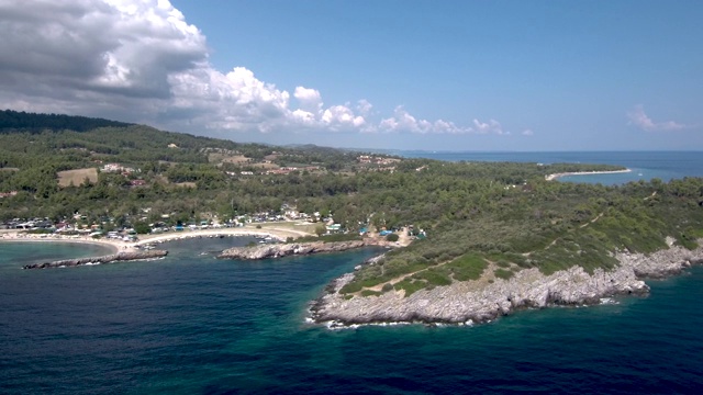 鸟瞰图与树木和岩石半岛，旁边的一个小海滩在Pefkohori Halkidiki，希腊，无人机的圆形运动视频素材